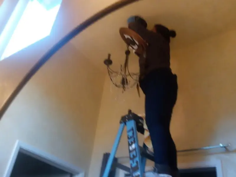 Electrician installing a chandelier in a Carroll residence
